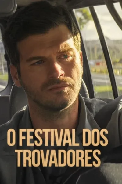 Homem barbudo e sério com olhos azuis, olhando à frente dentro de um carro. Luz solar forte destaca seu rosto; estrada e folhagem desfocadas ao fundo.