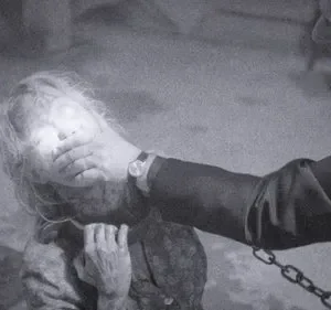 Imagem P&B. Homem com mão na boca de mulher com rosto etéreo e olhos brilhantes. Corrente à vista. Clima sombrio e tenso.
