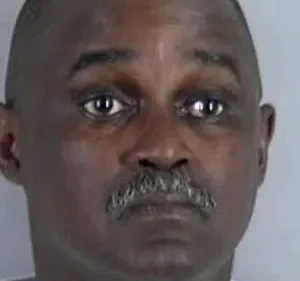 Close-up de um retrato de um homem negro de meia-idade com bigode. Fundo simples e neutro. Expressão séria. Espero que isso ajude! Avise-me se você precisar de mais ajuda.
