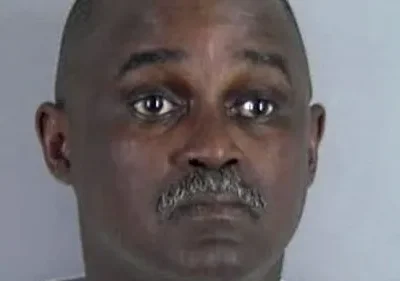 Close-up de um retrato de um homem negro de meia-idade com bigode. Fundo simples e neutro. Expressão séria. Espero que isso ajude! Avise-me se você precisar de mais ajuda.