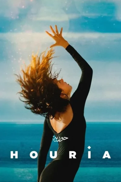 Mulher em traje preto, cabelo ao vento, braço estendido para o céu azul e o mar. Expressa euforia e liberdade.