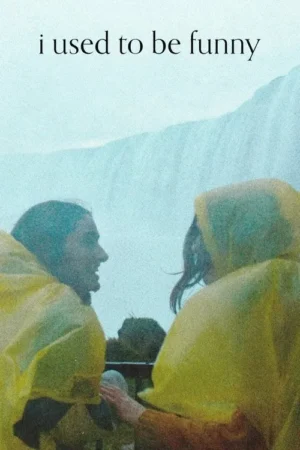 Duas pessoas em capas de chuva amarelas. Uma de perfil, a outra de costas toca seu braço. Fundo azul-claro e nebuloso. Clima íntimo.