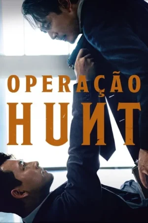 Dois homens em ternos. Um em pé aponta uma arma para o outro, que está caído e olha para cima. Cenário claro, clima de confronto.