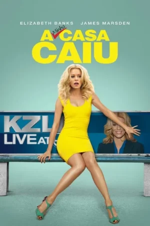 Mulher loira de vestido amarelo vibrante sentada em balcão de noticiário, expressão chocada. Outra mulher sorri atrás, mão esticada.