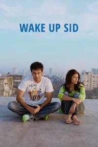 Um homem e uma mulher,em jeans,sentados num telhado. Ele de camiseta e tênis,ela de blusa verde e descalça,observam a cidade ao fundo.