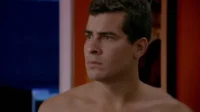 Homem sério e sem camisa olha para o lado. Fundo em tons de azul e vermelho sugere cenário moderno e tenso.