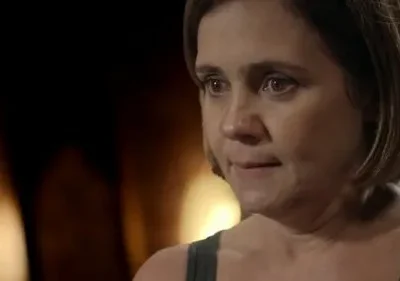 Pôster: Mulher de cabelo curto e olhos marejados em close-up, expressão triste e pensativa. Fundo escuro com luzes quentes e suaves.