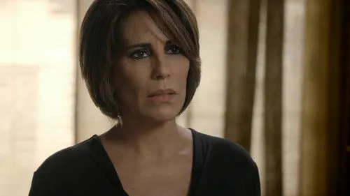 Babilônia – T01E39:Capítulo 39 1 Close-up de mulher com cabelo curto,maquiagem forte nos olhos e expressão preocupada,em um ambiente interno com luz suave.