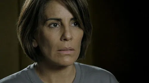 Babilônia – T01E42:Capítulo 42 1 Close-up de mulher com cabelo castanho curto e expressão preocupada. Ela olha para o lado contra fundo escuro.