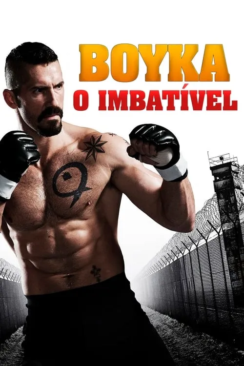 Homem musculoso e barbudo,com luvas de luta e tatuagens,posa com intensidade. Fundo com cerca de arame farpado e torre de prisão.