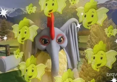 Criatura elefante cinza com crista, cercada por cabeças de elefante verde aladas e brilhantes. Fundo de montanhas e campo.