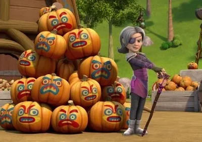 Mulher de tapa-olho, cabelo cinza e cajado sorri perto de pilha de abóboras com faces tribais. Cenário rural festivo.