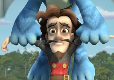 Homem de bigode e barba, visivelmente assustado, é segurado no ar pela mão de um grande monstro azul peludo. Cenário de floresta e céu.