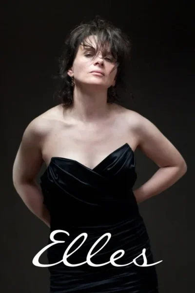 Mulher de cabelo desgrenhado em vestido preto tomara que caia. Ela tem um olhar intenso e sério contra um fundo escuro.