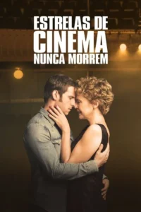 Homem jovem e mulher madura se abraçam intimamente,testas unidas,em fundo de palco/teatro com luzes quentes. Clima romântico.