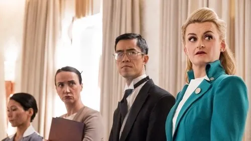 Expresso do Amanhã – T01E03:Acesso é poder 1 Quatro pessoas em ambiente formal. Uma mulher loira de jaqueta turquesa olha surpresa,os outros parecem sérios.