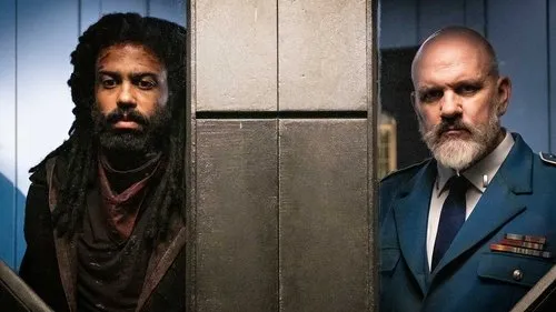 Expresso do Amanhã – T01E10:994 vagões 1 Dois homens sérios,um com dreads e roupa escura,outro careca com barba branca e uniforme militar,separados por um pilar metálico.