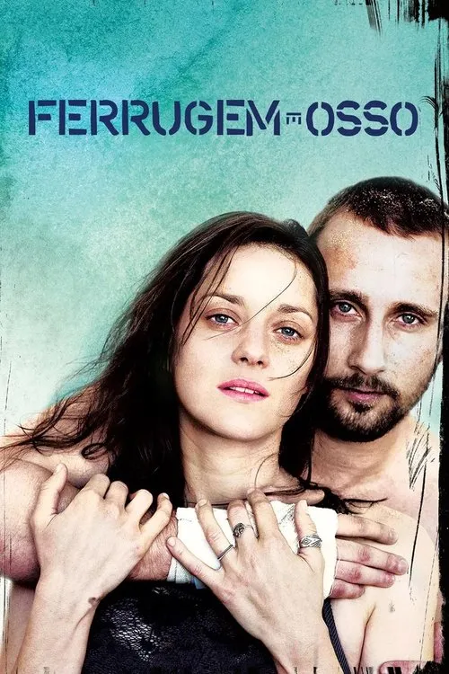 Mulher com mão enfaixada e homem barbudo abraçados,ambos com areia no rosto. Fundo azul-esverdeado áspero. Clima cru e intenso.