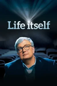Homem de óculos e cabelos grisalhos,em um cinema,olha para cima. Um facho de luz do projetor ilumina a cena escura.