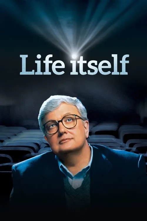 Homem de óculos e cabelos grisalhos,em um cinema,olha para cima. Um facho de luz do projetor ilumina a cena escura.