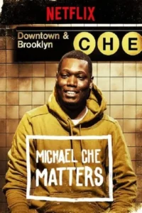 Homem negro sorridente em moletom amarelo, em metrô. Letreiro Downtown & Brooklyn e círculos amarelos. MATTERS na camisa.