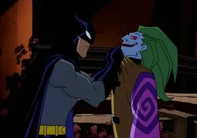 Um herói de capa escura segura um vilão de pele azul, cabelo verde e sorriso macabro pelo pescoço. Cenário urbano e sombrio.