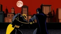 Luta animada: vigilante de capa escura e figura blindada amarela/preta no telhado da cidade. Céu vermelho-sangue, lua cheia.