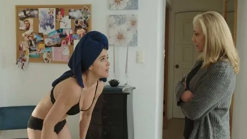 Mulher de lingerie e toalha na cabeça confronta mulher loira de braços cruzados, em quarto. Clima tenso.