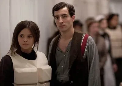 Jovem mulher séria de colete salva-vidas branco e homem pensativo de colete escuro. Pessoas borradas ao fundo, em cenário histórico de emergência.