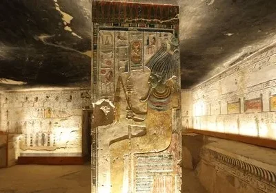 Tumba egípcia. Pilar e paredes com murais coloridos, figura divina central. Luz quente. Clima misterioso.