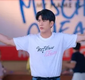 Jovem asiático com camiseta branca e braços abertos num local casual. Fundo tem graffiti azul. Cena vibrante e expressiva.