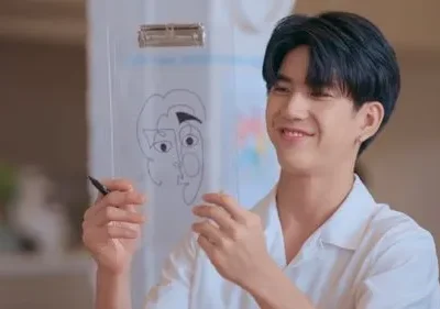 Homem sorridente de camisa branca desenha rosto abstrato em prancheta transparente. Clima divertido e criativo.