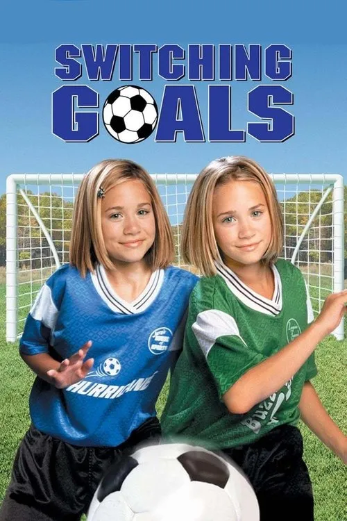 Duas jovens idênticas em uniformes de futebol (azul e verde) sorriem num campo. Uma bola na frente e um gol atrás. Clima alegre.