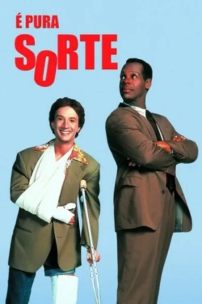 Dois homens em fundo azul. Um branco, sorrindo, com braço engessado, muletas e gesso na perna. O outro negro, sério, de terno e braços cruzados.