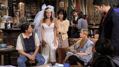 Noiva sorridente em vestido branco e véu entre amigos em um café. Ambiente acolhedor e descontraído com o grupo reunido.