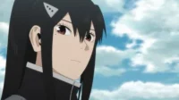 Kaiju No. 8 – T01E21:Presságio 2 Close-up de mulher anime de cabelo preto,olhos avermelhados e uniforme escuro. Expressão séria,fundo de céu azul com nuvens.