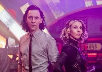 Homem de cabelos escuros e mulher loira, ambos sérios, contra um fundo urbano futurista com luzes neon roxas e amarelas.