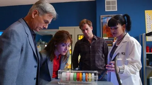 Quatro investigadores,incluindo uma cientista,num laboratório,olham focados um objeto transparente com faixas coloridas.