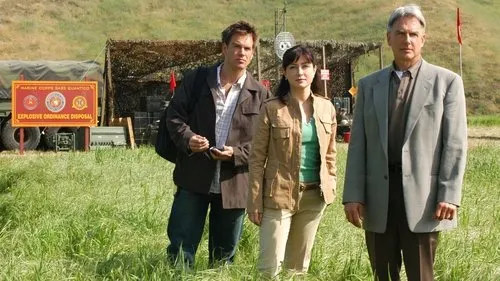 NCIS:Investigação Naval – T01E20:Desaparecido 1 Três figuras sérias posam em campo verde. Ao fundo,um caminhão e um aviso Explosive Ordnance Disposal.