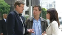 NCIS:Investigação Naval – T01E23:Toque de Alvorada 1 Três profissionais conversam intensamente numa rua da cidade. Um homem de terno com laço,um jovem de jaqueta e uma mulher de blazer.