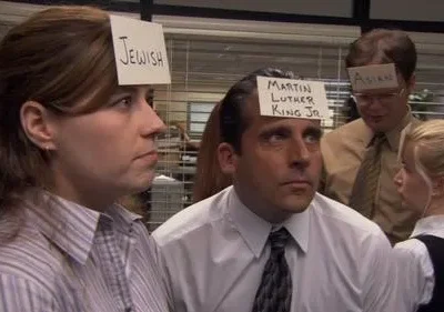 Funcionários em um escritório com etiquetas na testa, como Jewish e Martin Luther King Jr.. Olhares confusos em um ambiente de trabalho.