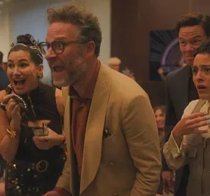 Grupo de pessoas em um evento social reage com surpresa e choque intensos. Um homem e duas mulheres expressam forte emoção.