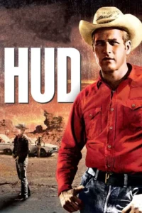 Homem sério de chapéu de cowboy e camisa vermelha. Ao fundo, deserto, outro homem e carros parados. Ambiente árido e dramático.