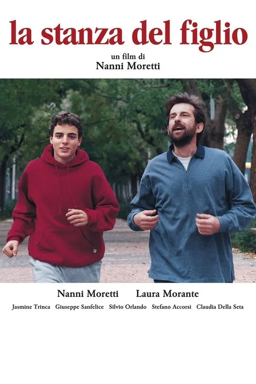Jovem de moletom vermelho e homem barbudo de camisa azul correm por um caminho arborizado. Ambos sorriem. Clima de leveza e atividade.