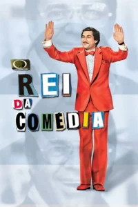 Homem bigodudo sorridente de terno vermelho e gravata borboleta,braços erguidos. Fundo azul claro com silhueta e letras coloridas. Clima cômico.