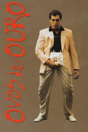 Jovem em blazer rosa claro, camisa preta aberta, calça branca e cabelo penteado, mão na virilha. Fundo neutro. Provocador.