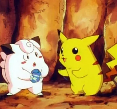 Duas criaturas animadas interagem numa caverna. Uma rosa-claro segura um item, a outra, amarela com cauda de raio, gesticula.