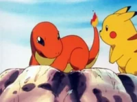 Criatura laranja com cauda de fogo e criatura amarela com bochechas vermelhas sobre rochas, céu azul ao fundo. Clima amigável.