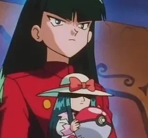 Mulher de anime com cabelo escuro e jaqueta vermelha, expressão séria, segurando uma boneca com chapéu e uma esfera vermelha e branca. Fundo escuro.