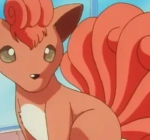 Animal laranja-acastanhado, parecido com uma raposa, com seis caudas encaracoladas e orelhas pontudas. Olhos curiosos, sentado em um quarto claro com planta.